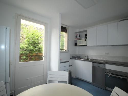 une cuisine avec des armoires blanches, une table et une fenêtre dans l'établissement Grand appart. avec terrasse à 300m de la plage à Collioure - FR-1-309-261, à Collioure