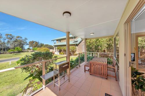 an empty porch with a table and bench on a balcony at Ingenia Holidays Merry Beach in Kioloa