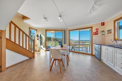 a kitchen with a table and chairs and windows at Ingenia Holidays Merry Beach in Kioloa