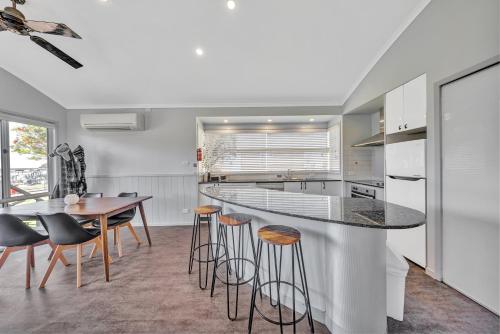 a kitchen with a bar with stools and a table at Ingenia Holidays Merry Beach in Kioloa