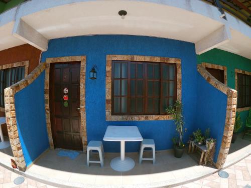 Habitación azul con mesa y 2 taburetes en Vila da Drika en Rio das Ostras