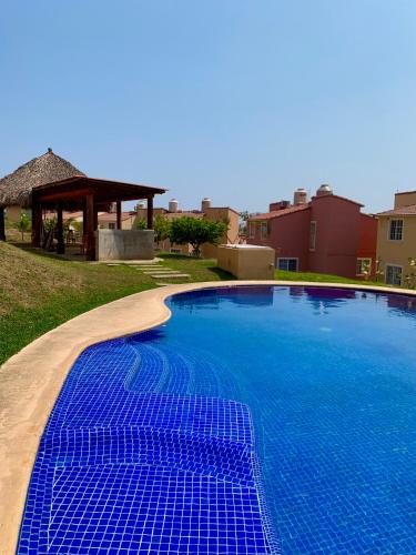 a large blue swimming pool with a gazebo at sweet home ixtapa comfort in Ixtapa