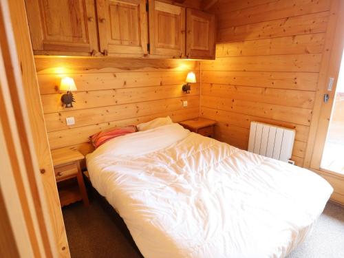 une chambre avec un lit blanc et un mur en bois dans l'établissement Chalet cosy aux Gets, proche du lac avec sauna et parking privé - FR-1-623-58, aux Gets