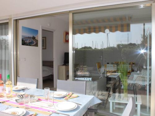une salle à manger avec une table et une fenêtre en verre dans l'établissement Appartement 3P en RDJ avec Jardin et Terrasse, à 5 min Plage et Restaurants, Parking Privé, Climatisé - FR-1-252A-59, à Villeneuve-Loubet