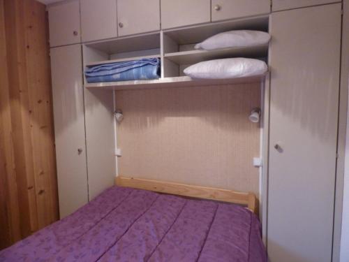 Cette petite chambre comprend un lit et quelques étagères. dans l'établissement Appartement skis aux pieds, cosy 2 pièces, terrasse Sud/Est, 1er étage, idéal pour 4 personnes - FR-1-458-131, au Grand-Bornand