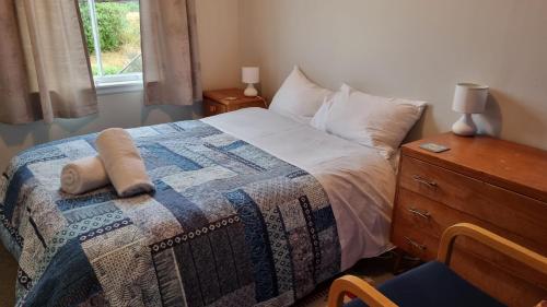 a bedroom with a bed and a dresser and a window at The Tussocks, Arthur's Pass in Arthur's Pass