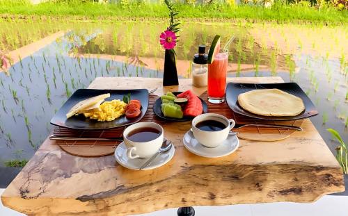 un tavolo con piatti e due tazze di caffè di Sri Lestari Banyuatis a Munduk