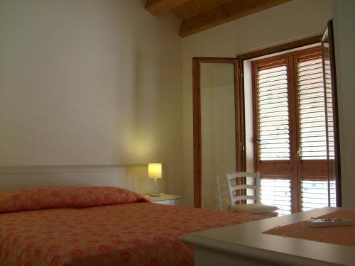 um quarto com uma cama, uma mesa e uma janela em Casa Vacanze Puccia em Modica