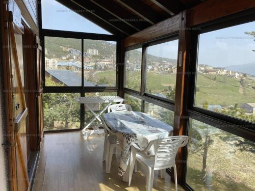 une pièce avec une table, des chaises et des fenêtres dans l'établissement Chalet 6 pers. Les Angles avec garage et véranda - FR-1-295-136, aux Angles