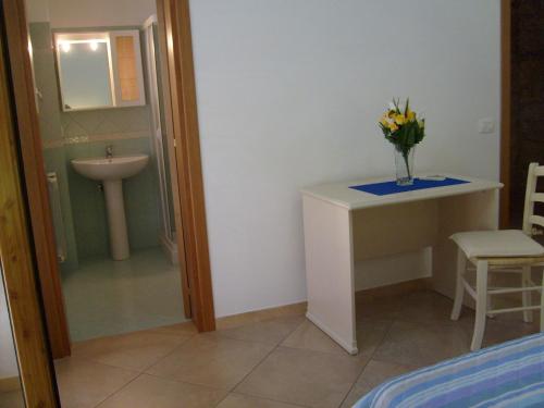 un baño con lavabo y un jarrón de flores sobre una mesa en Casa Vacanze Puccia, en Módica