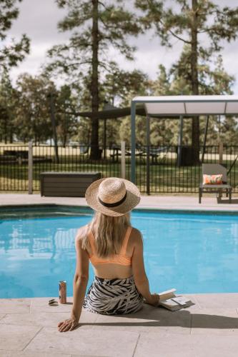 a woman in a hat sitting next to a swimming pool at Palmers Lane Estate Hunter Valley in Pokolbin