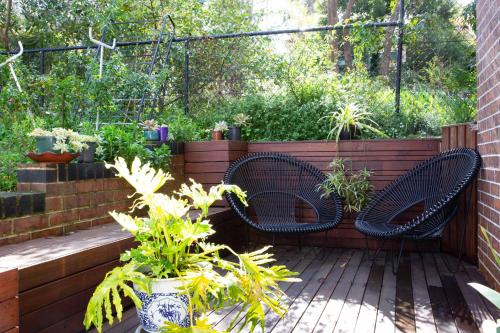 two wicker chairs sitting on a deck with plants at The roses house - Cozy and Modern house in Katoomba in Katoomba