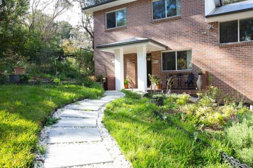 a garden with a path leading to a house at The roses house - Cozy and Modern house in Katoomba in Katoomba