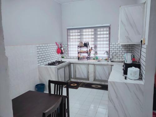 a white kitchen with a sink and a table at Yoni Homestay in Kampung Raja
