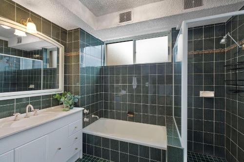 a bathroom with a tub and a sink and a mirror at Regency Court 4 in The Entrance
