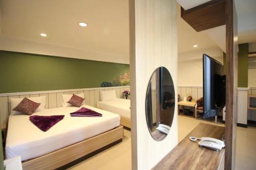 a bedroom with a bed and a tv and a mirror at Kaya Place in Bangkok