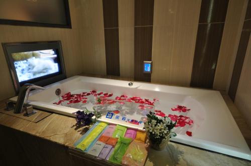 a bath tub filled with red flowers and a tv at 采岩汽車旅館 in Taichung