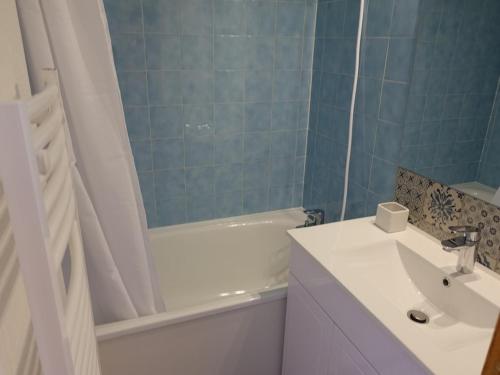 La salle de bains est pourvue d'un lavabo blanc, d'une baignoire et d'une douche. dans l'établissement Appartement refait à neuf avec piscine, près des pistes, pour 4 personnes - FR-1-342-257, à Beaufort