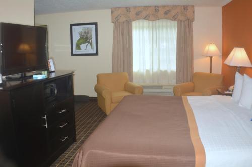 a hotel room with a bed and a flat screen tv at Baymont by Wyndham Muskegon in Muskegon