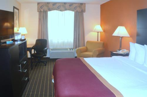 a hotel room with a bed and a large window at Baymont by Wyndham Muskegon in Muskegon