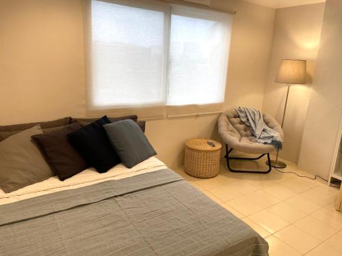a bedroom with a bed and a chair and a window at CRIB 227: Modern Fresh Vibe Condo in Olongapo