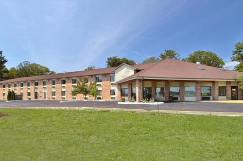 a large brick building with a grass field in front at Baymont by Wyndham Muskegon in Muskegon