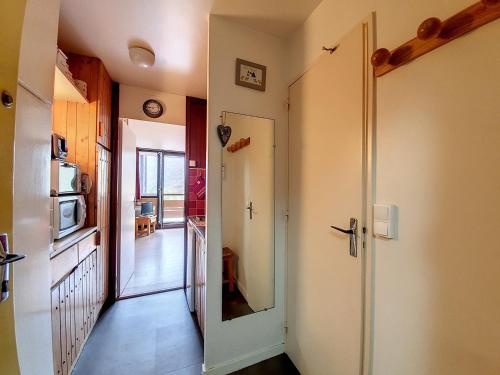 un couloir avec une porte menant à une cuisine équipée d'un four micro-ondes dans l'établissement Studio idéalement situé, 2 pers, pied des pistes - FR-1-178-355, aux Menuires