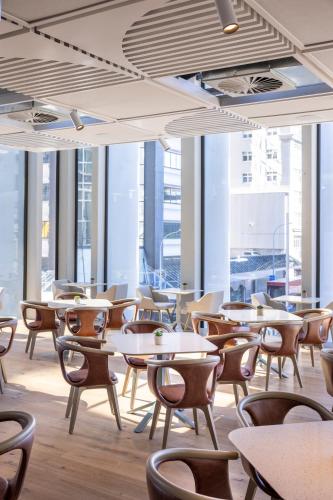 a restaurant with tables and chairs and large windows at Holiday Inn Express Auckland City Centre by IHG in Auckland