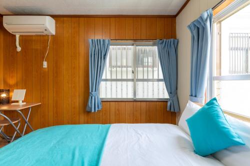 a bedroom with a bed and a window with blue curtains at M`Sリゾート若狭@LiB PLUS in Tomari