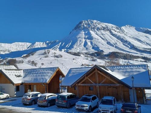 Une montagne enneigée avec des voitures garées dans un parking dans l'établissement Appartement confortable, 300m des pistes et commerces, balcon sud, parking, animaux acceptés - FR-1-618-14, à Albiez-Montrond
