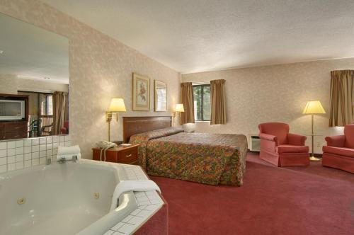 a hotel room with a bed and a bath tub at Baymont by Wyndham Muskegon in Muskegon