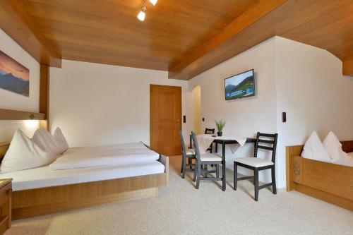 a bedroom with a bed and a table and chairs at Landhaus zum Griena in Mayrhofen