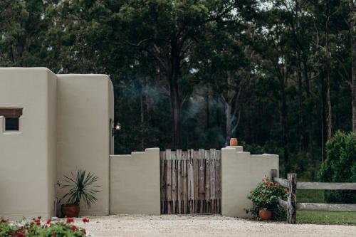 uma cerca branca com um portão de madeira e flores em Casa La Vina Villas Pokolbin em Pokolbin