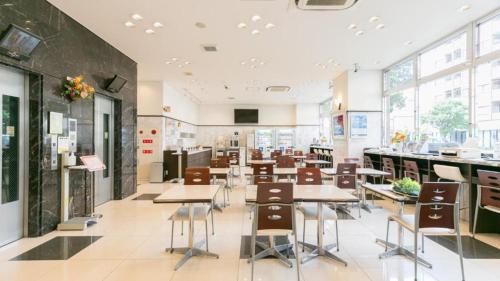a cafeteria with tables and chairs in a building at Toyoko Inn Kumagaya eki Kita guchi in Kumagaya