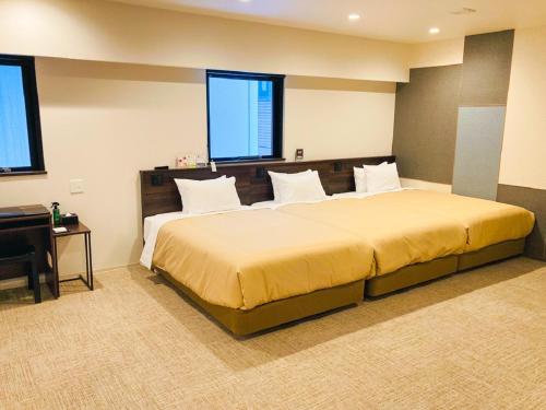 札幌的住宿－HOTEL LiVEMAX PREMIUM Sapporo Odorikoen，一间卧室设有一张大床和两个窗户。
