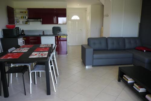 a kitchen and a living room with a couch and a table at La Résidence Les Grands Vignobles in Libourne