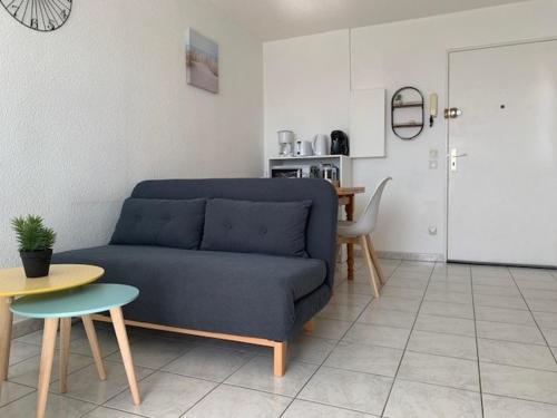 un salon avec un canapé bleu et une table dans l'établissement Appartement climatisé à Balaruc-les-Bains avec balcon, parking et animaux admis - FR-1-503-127, à Balaruc-les-Bains