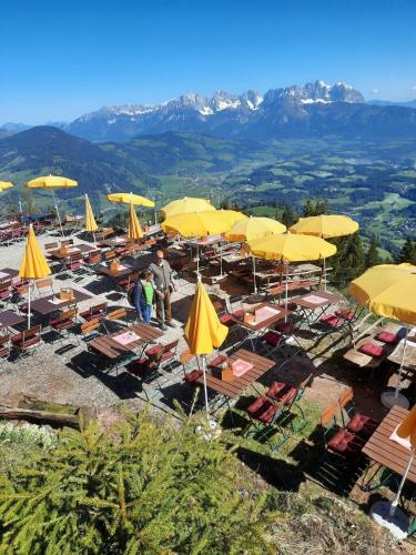 a group of tables and chairs with yellow umbrellas at Hocheckhuette On Top of the Kitzbuehel Hahnenkamm Mountain in Kitzbühel