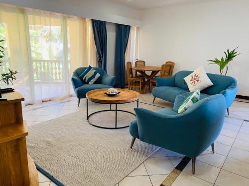 a living room with blue chairs and a table at Pieds Dans L’Eau Holiday Apartments in Mahe