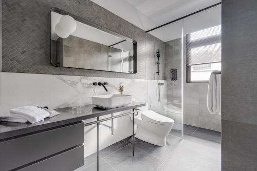 a bathroom with a sink and a toilet and a mirror at The Denizen 真寓 in Taipei