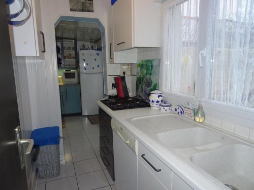 une cuisine blanche avec un évier et une cuisinière dans l'établissement Rez-de-Jardin T3/4 avec Jardin, Parking Privé - Proche Plage et Centre-ville - FR-1-92-910, à Les Sables-dʼOlonne