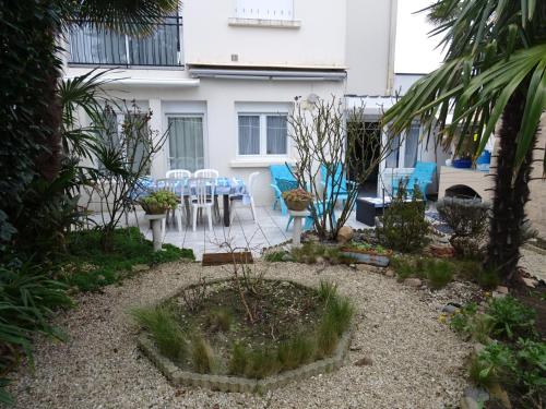 - un jardin avec une table et des chaises en face d'un bâtiment dans l'établissement Rez-de-Jardin T3/4 avec Jardin, Parking Privé - Proche Plage et Centre-ville - FR-1-92-910, à Les Sables-dʼOlonne
