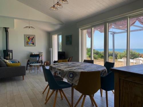 - un salon avec une table et des chaises offrant une vue sur l'océan dans l'établissement Maison vendéenne rénovée, accès direct plage, terrasses, BBQ, parking gratuit - FR-1-336-123, à Longeville-sur-Mer