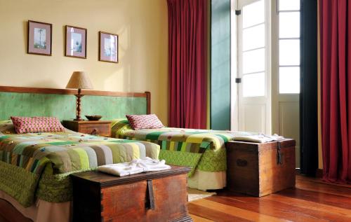 a bedroom with two beds and a window with red curtains at Hotel Villa Bahia in Salvador