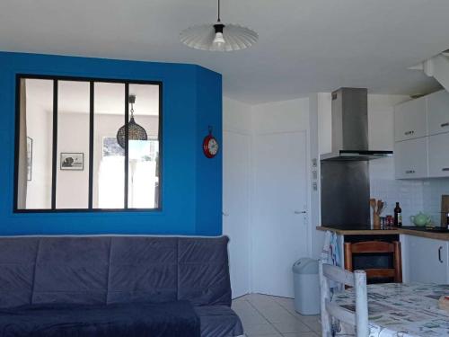 un salon avec un canapé et un mur bleu dans l'établissement Maison Proche Plage avec Jardin, Terrasse et WIFI à Le Palais - Parfait pour Familles - FR-1-418-182, au Palais