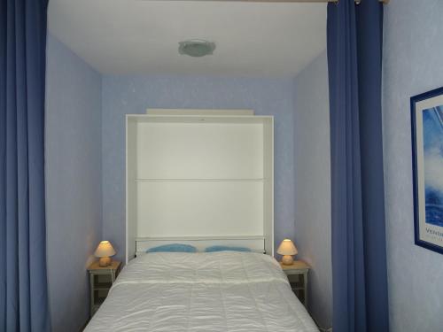 - une chambre avec un lit avec des rideaux bleus et 2 lampes dans l'établissement Appartement Les Sables-d'Olonne, 1 pièce, 4 personnes - FR-1-92-915, à Les Sables-dʼOlonne