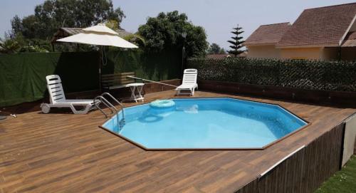 a pool on a deck with two chairs and an umbrella at West Vally Villa - Casa West in Panchgani