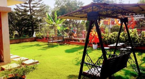 a green yard with a bench and an umbrella at West Vally Villa - Casa West in Panchgani