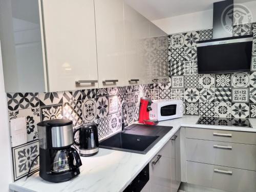 a kitchen with black and white tiles on the wall at Gîte tout inclus avec jardin clos, terrasse privative, proche forêt et randonnées, 1 chambre, 1 canapé-lit - FR-1-510-168 in Preux-au-Bois