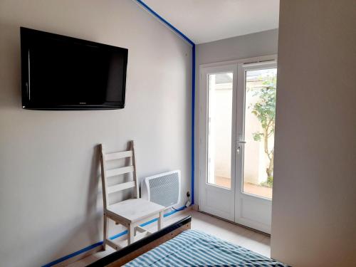 une pièce avec une chaise et une télévision sur un mur dans l'établissement Appartement T2 à Arcachon près du centre et de la plage avec parking et terrasse - FR-1-319-465, à Arcachon